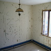 An abandoned room featuring a broken window and scattered, damaged furniture.
