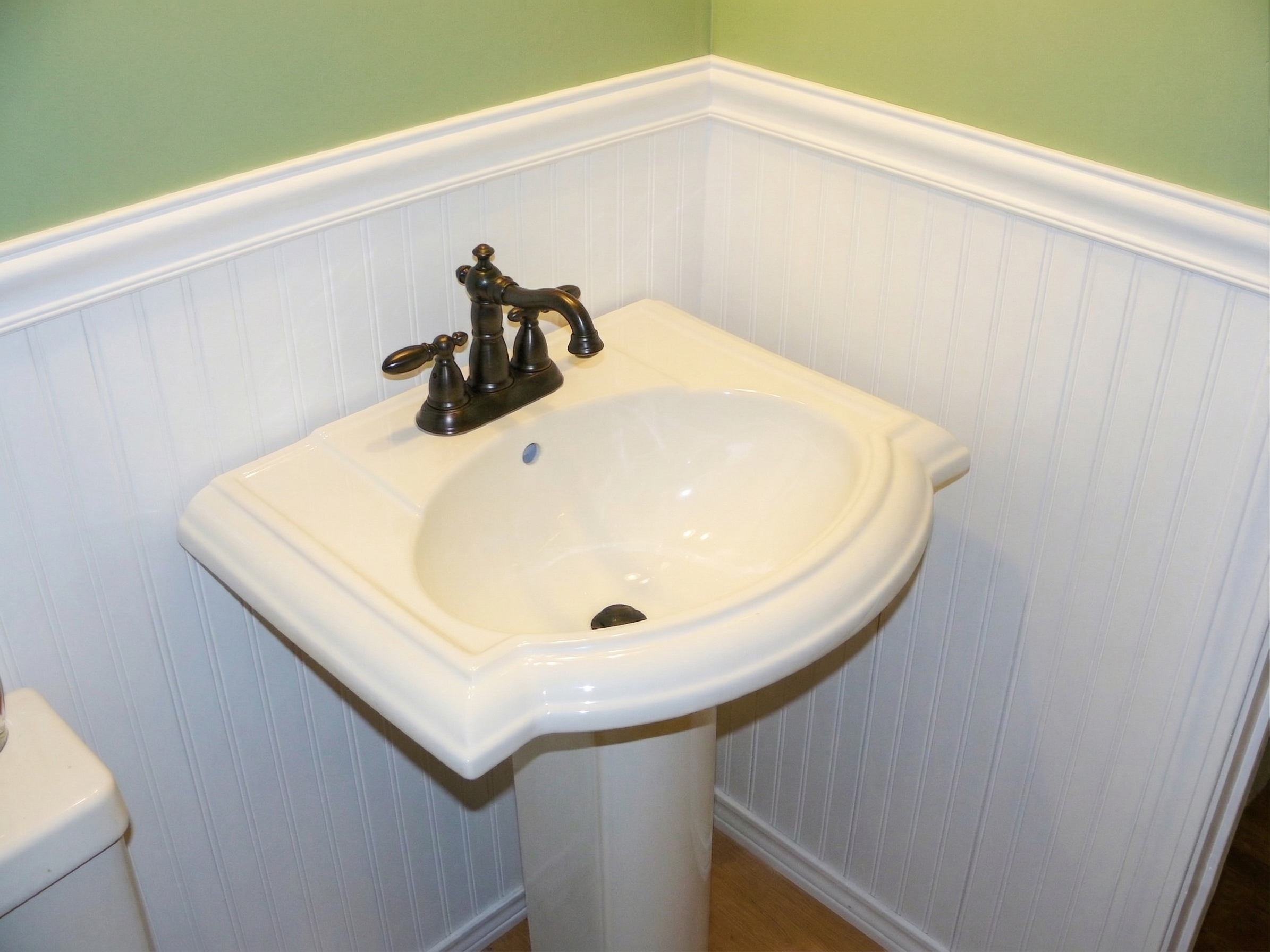 Bathroom showing sink with white backsplash and green paint after renovation